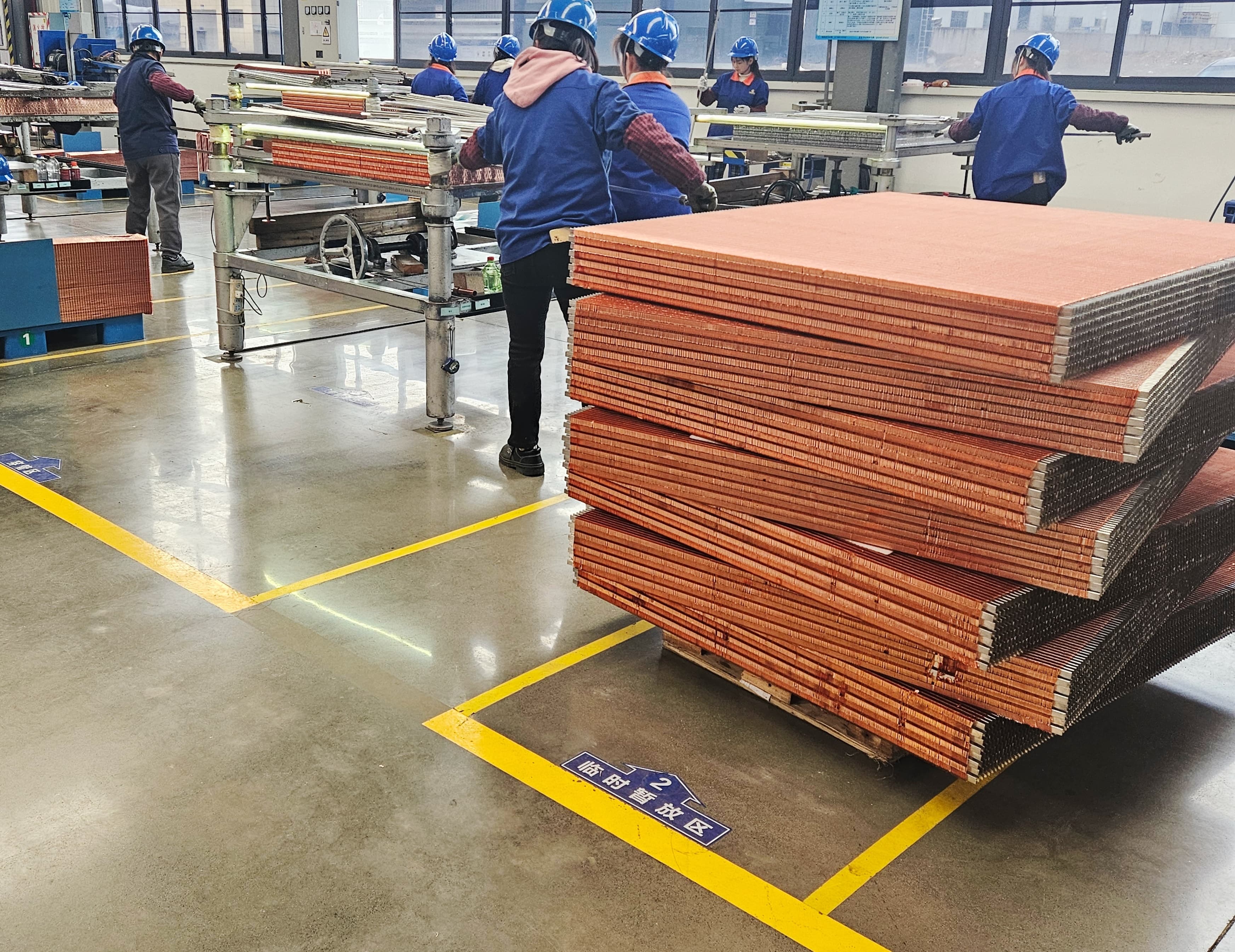C&ocirc;ng nh&acirc;n đang xử l&yacute; c&aacute;c l&otilde;i tản nhiệt v&acirc;y đồng xếp chồng l&ecirc;n nhau trong nh&agrave; m&aacute;y Sinrui