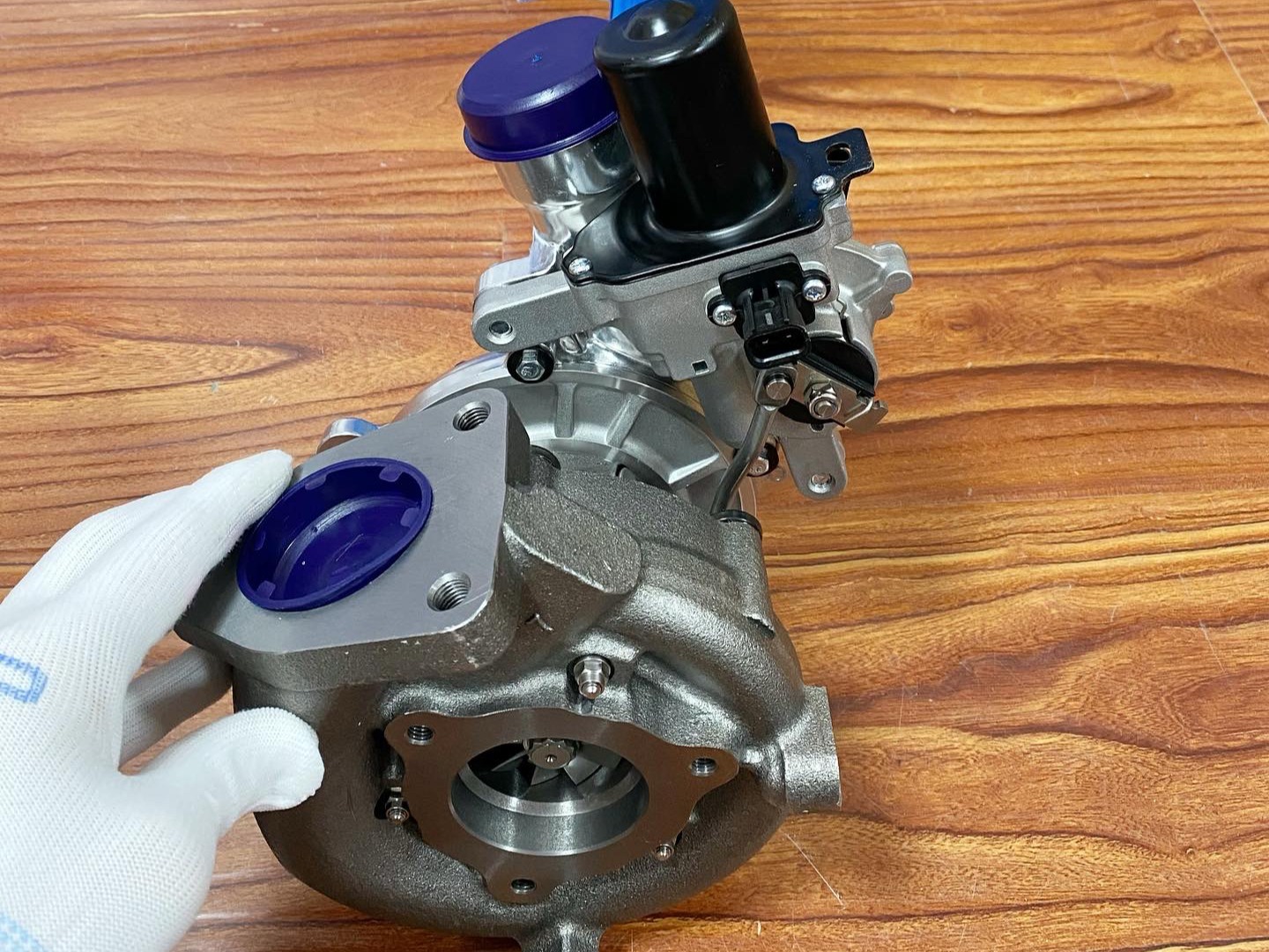 montaż turbosprężarki z ręką w rękawiczce, prezentujący precyzję inż